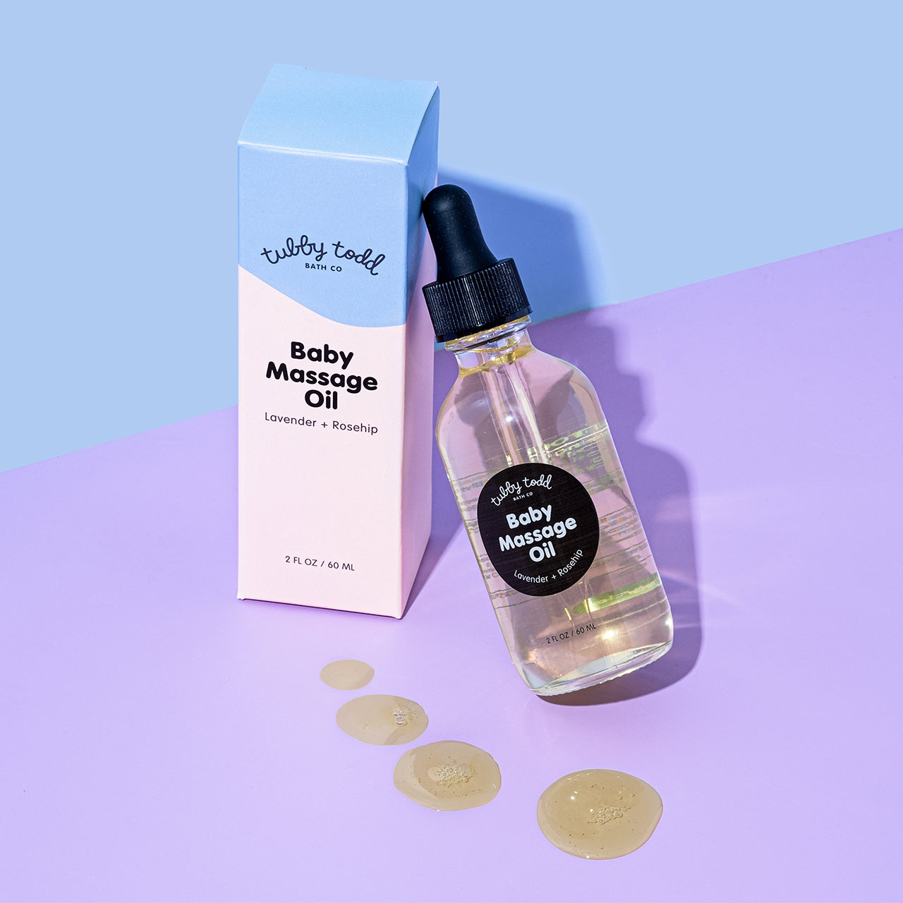 A box of new baby massage oil is standing and bottle leaning against the box and texture is shown on the floor.